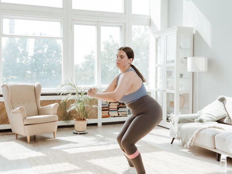 Person stretching in a bright room with golden sunlight.