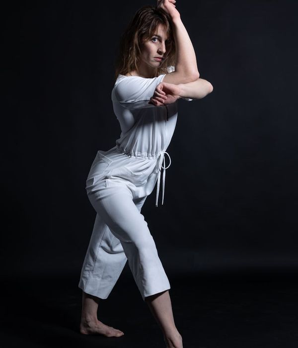 Woman performing a graceful yoga balance pose in dark studio.